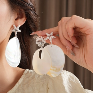 Macro detail of iridescent shell dangle earring with starfish stud and metal shell link