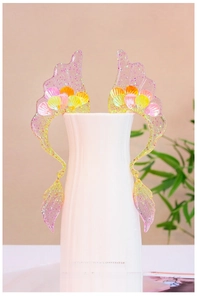 Detail of wing-shaped silicone mold with glittery resin ear cuff on white porcelain vase