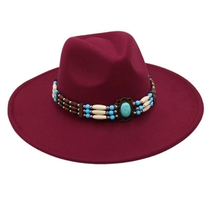 Close-up of burgundy felt hat featuring intricate turquoise beadwork and a vintage metal gem