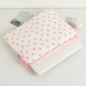 Detailed view of quilted laptop sleeve with pink bow pattern and metallic zipper closure