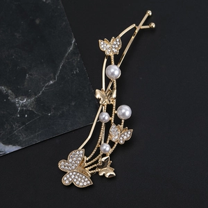Close-up of golden metal hairpin featuring rhinestone butterflies and white pearls on black
