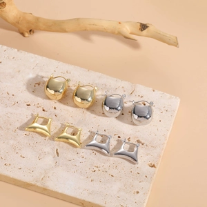 Detailed close-up of 14K gold and silver hoop earrings on a stone textured slab display
