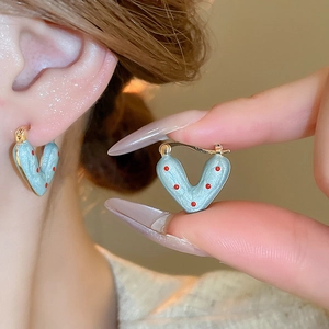 Detail of vintage heart-shaped blue enamel earrings with red polka dots and gold trim