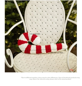 Detail of red and white candy cane plush pillow on chair with festive Christmas tree lights