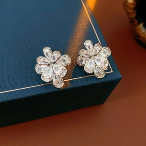 Dettaglio degli orecchini a fiore in argento con zirconi su una scatola di gioielli blu