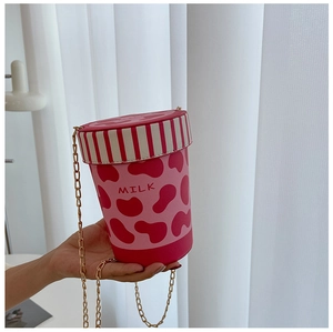 Detail of pink milk cup bucket bag featuring cow print pattern and gold metal chain strap