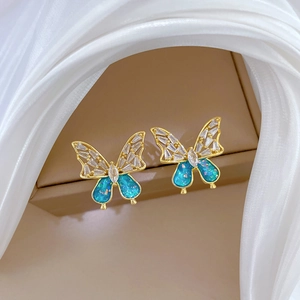 Close-up of elegant gold butterfly earrings with blue glitter and white crystals