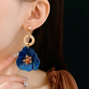 Detail of vintage flower earring with blue petals and amber bead on a gold ring hoop