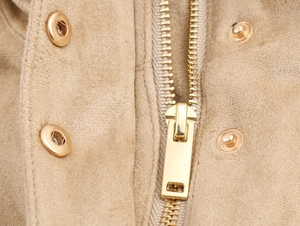 Détail de la fermeture éclair dorée et du bouton pression sur veste en daim kaki