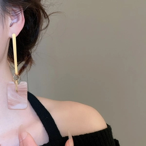 Close-up of model wearing geometric square earrings with pink marble resin pendants