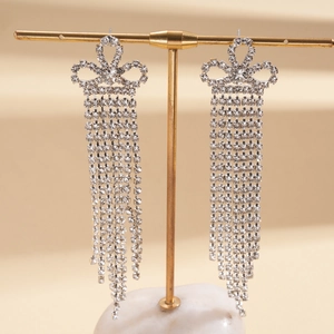 Gros plan de boucles d'oreilles à pompons argentés avec cristaux blancs sur un support doré