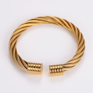 Macro view of gold twisted wire cable bracelet with cylindrical end caps and texture