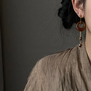 Macro detail of long resin tiger eye pendant earrings on a model with vintage aesthetic