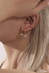 Close-up of gold clover earrings with micro-inlaid zircon crystals on a female model