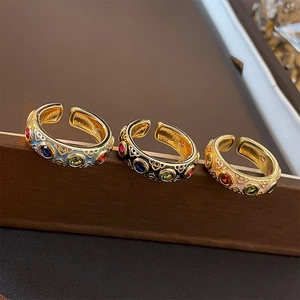 Close-up of three vintage enamel open rings with colorful gemstones on a display stand