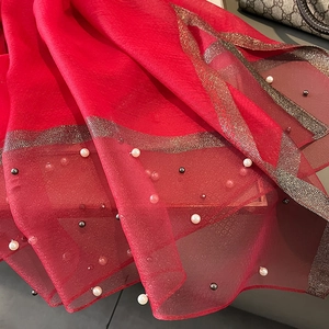 Detailed macro view of red silk shawl with exquisite pearl beading and golden metallic lace