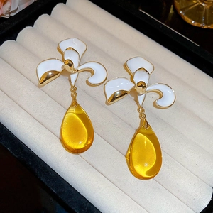 Detail of white flower earrings with amber teardrop charms in a jewelry box display