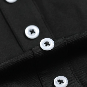 Détail de boutons blancs à quatre trous sur une robe noire ajustée en tissu texturé