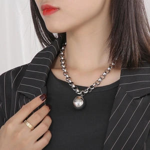 Détail du collier chaîne épaisse en acier argenté avec pendentif boule et bague bicolore