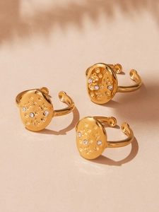 Detail of vintage 18k gold plated open rings with star zircon inlay and embossed texture