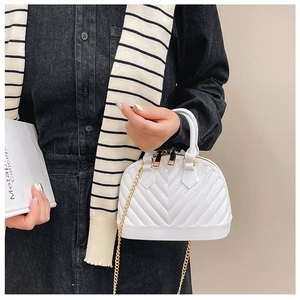 Close-up of a white glossy mini shell bag with V-quilted stitching and gold chain strap