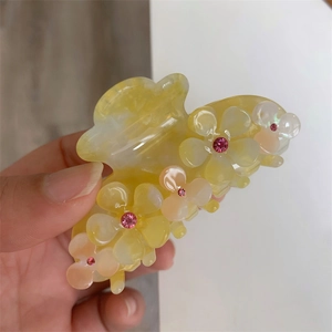 Close-up of translucent yellow flower hair claw clip with pink gemstone centers