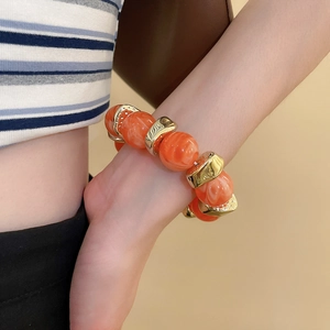 Close-up of stylish round acrylic beaded bracelet with orange marbling and gold accents
