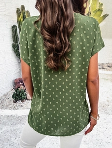 Detail view of women's green polka dot V-neck top showing the back texture and fabric