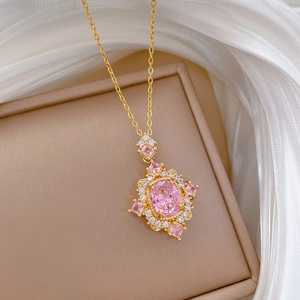 Detailed shot of a gold necklace featuring a pink oval gemstone on silk fabric