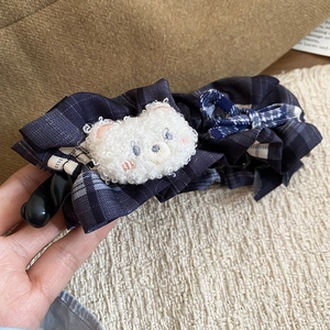 Détail d'une pince à cheveux avec nœud à carreaux bleus et tête d'ours en peluche