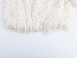 Détail d'une veste en peluche blanche montrant la texture douce des fibres et des plumes