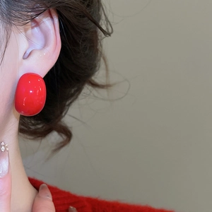 Macro detail of red acrylic teardrop earring on model matching with red knitwear