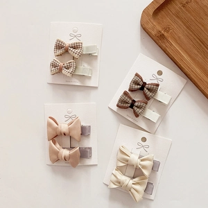 Detail of four sets of fabric bow hair clips for girls in plaid and satin textures