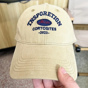 Detailed view of 3D embroidery on a beige cotton baseball cap with blue and red letters