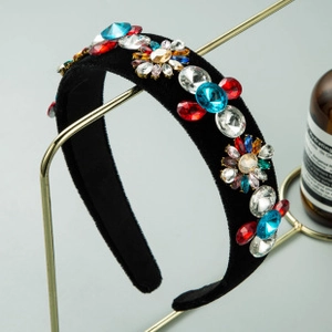 Dettaglio di cerchietto in velluto nero con strass colorati su supporto dorato