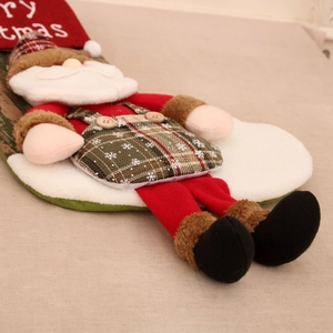 Detail of red and green Christmas stocking with 3D Santa doll and plush fabric textures