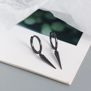 Macro view of black punk style cone spike earrings on a minimalist artistic background