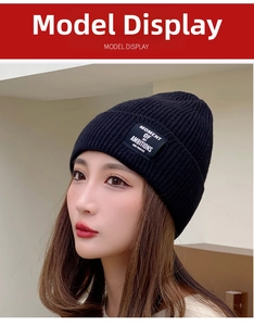 Close-up of black knitted beanie featuring a square woven label with white text