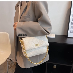 Close-up of a white quilted crossbody bag with a gold chain strap and metal lock
