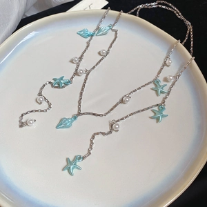 Détail du collier étoile de mer et coquillage avec pendentifs bleus et perles blanches