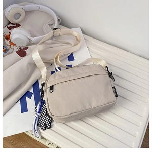 Détail du sac bandoulière en nylon beige avec sangle réglable et accessoire de mode