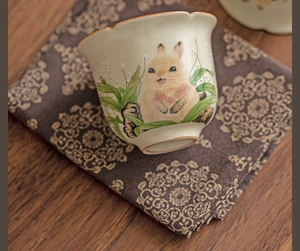 Detailed top view of a ceramic Ru kiln tea cup with rabbit motifs and orange rim