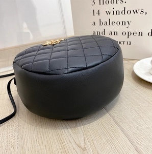 Detailed close-up of a black quilted semi-circular bag with elegant gold metal charm