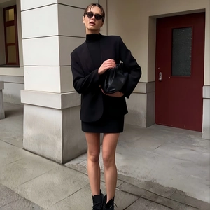 Full street style shot of a solid black oversized blazer jacket with a matching mini skirt
