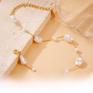 Close-up of golden stainless steel chain with irregular baroque pearls and lobster clasp