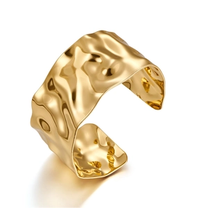 Detail of a wide gold cuff bracelet with modern hammered texture and irregular wave edges