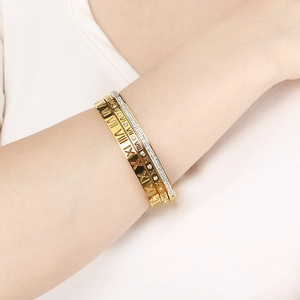 Close-up of stacked gold and silver bangles with Roman numerals and shimmering crystals