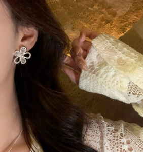 Close-up of elegant hollow flower stud earrings with a pearl center on a female model