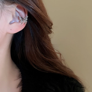 Detail view of a silver butterfly ear cuff with sparkling zircon stone on the ear