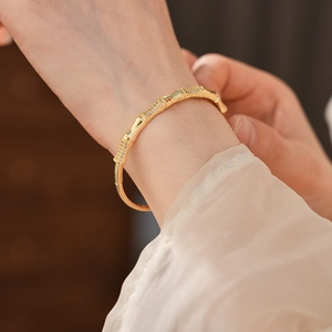 Detail of gold bamboo-shaped bangle with micro-paved zircons on a model's wrist